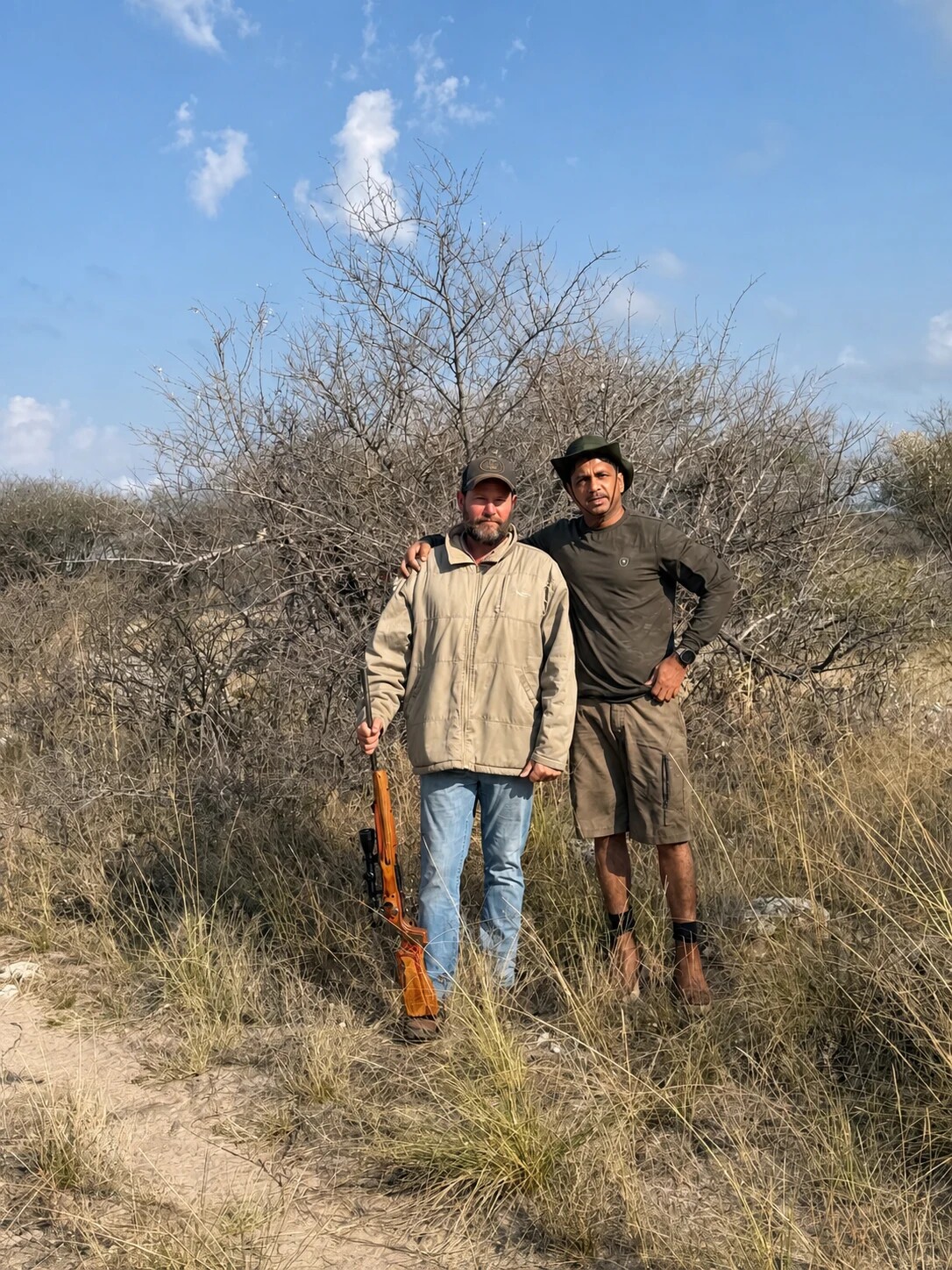 A visiting hunter with a member of the Botswana field team and a scoped rifle