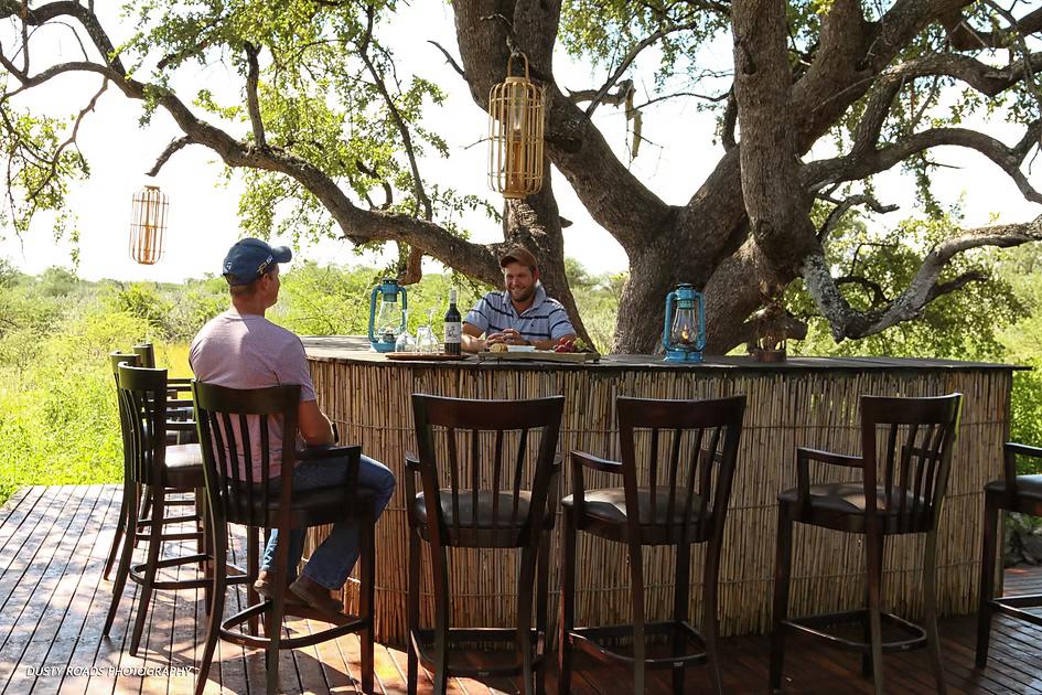 Safari hosts preparing the open-air Botswana camp bar